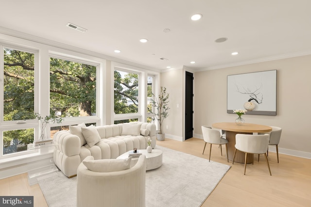 living room with light hardwood / wood-style floors, crown molding, and a healthy amount of sunlight