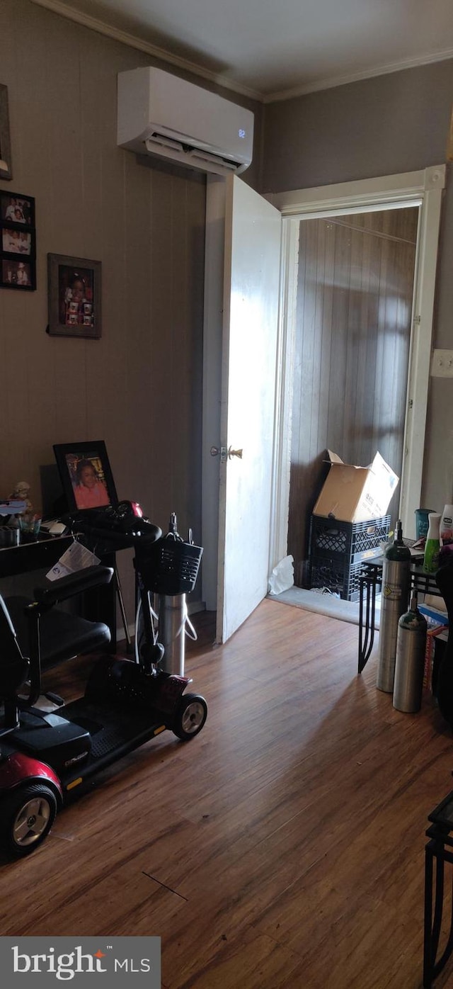 interior space featuring ornamental molding, a wall mounted AC, wood-type flooring, and wood walls