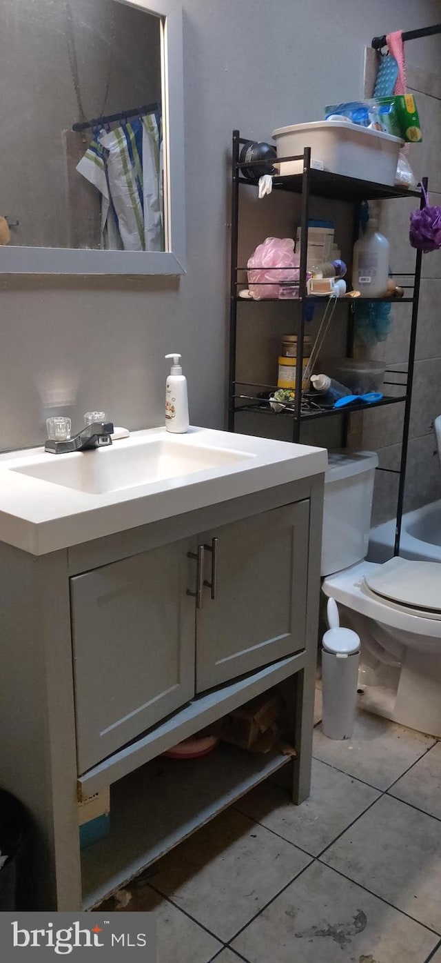 full bathroom featuring tiled shower / bath, vanity, toilet, and tile patterned flooring