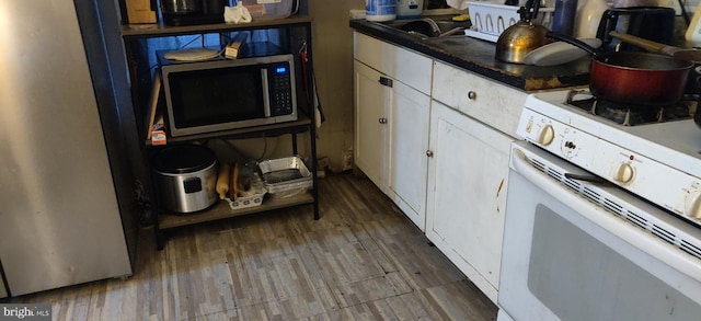 kitchen featuring sink, hardwood / wood-style floors, white cabinetry, and white stove