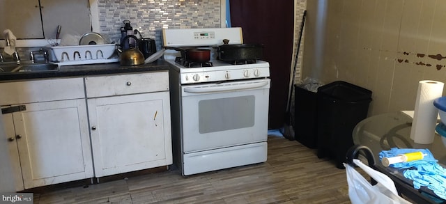 kitchen with white cabinets, white gas stove, hardwood / wood-style flooring, and sink