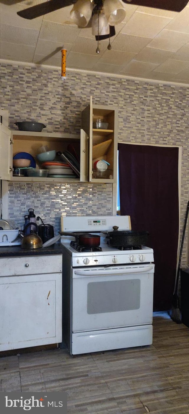 kitchen with white gas range oven, tasteful backsplash, dark hardwood / wood-style flooring, and white cabinets