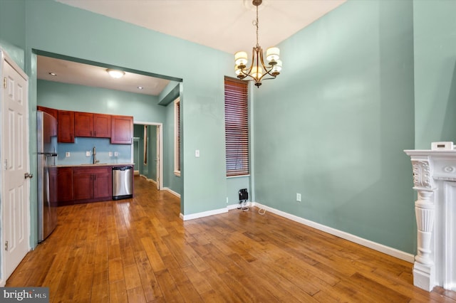 kitchen with decorative light fixtures, appliances with stainless steel finishes, hardwood / wood-style floors, and sink