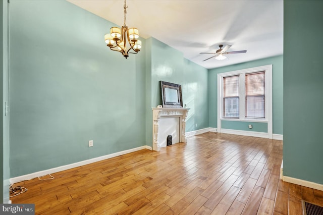 unfurnished living room with ceiling fan with notable chandelier and wood-type flooring