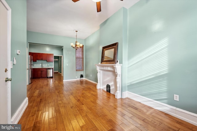 unfurnished living room with ceiling fan with notable chandelier and hardwood / wood-style floors