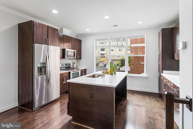 kitchen with a kitchen island with sink, dark wood-type flooring, sink, crown molding, and appliances with stainless steel finishes