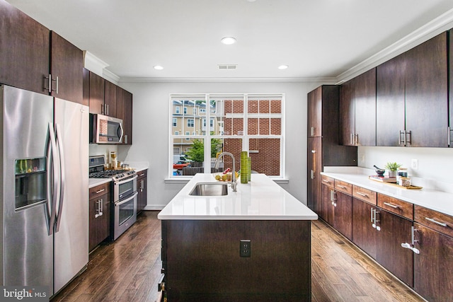 kitchen with an island with sink, dark brown cabinetry, stainless steel appliances, sink, and dark hardwood / wood-style flooring