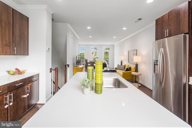 kitchen with dark brown cabinetry, dark wood-type flooring, sink, ornamental molding, and stainless steel fridge with ice dispenser