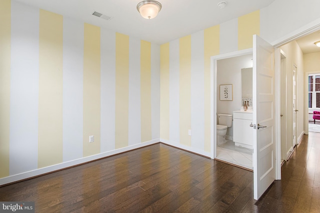 interior space with ensuite bathroom and dark wood-type flooring