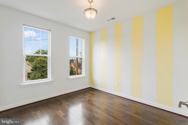 empty room with dark hardwood / wood-style flooring and a healthy amount of sunlight