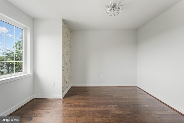 spare room featuring an inviting chandelier and dark hardwood / wood-style floors