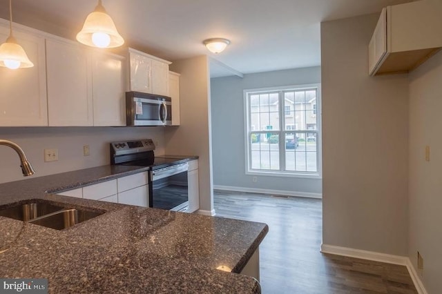 kitchen featuring white cabinets, hanging light fixtures, sink, stainless steel appliances, and dark stone countertops