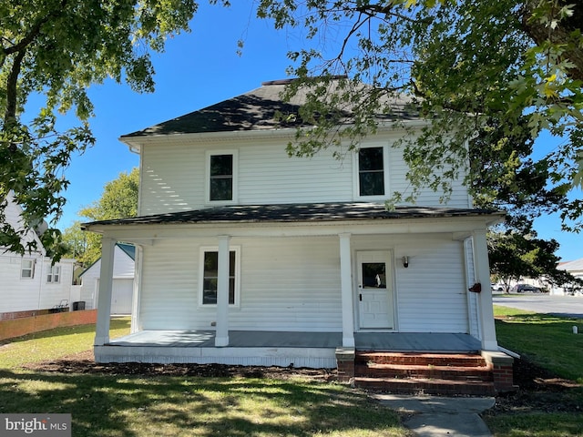 rear view of property featuring covered porch and a yard