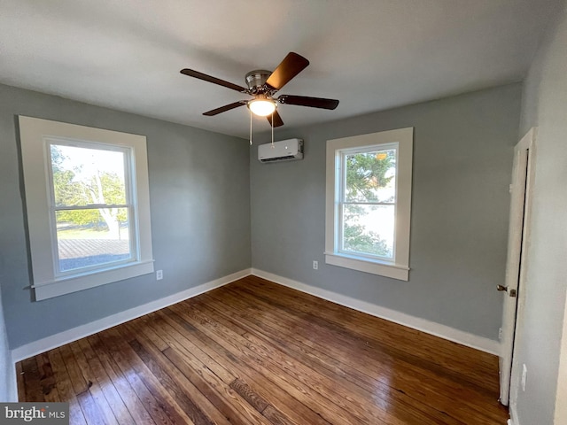 spare room featuring ceiling fan, a wall mounted AC, plenty of natural light, and hardwood / wood-style floors