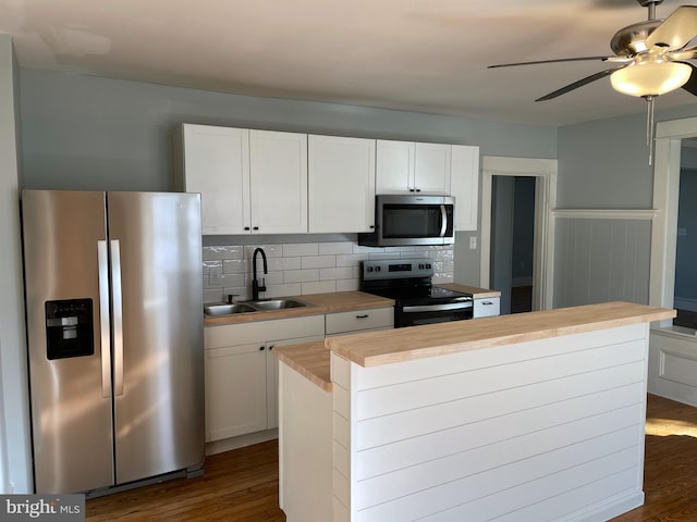 kitchen with appliances with stainless steel finishes, white cabinets, sink, and dark hardwood / wood-style floors