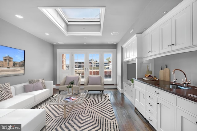 living room featuring dark hardwood / wood-style flooring, sink, and a skylight