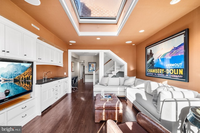 living room featuring dark hardwood / wood-style floors, sink, and a skylight