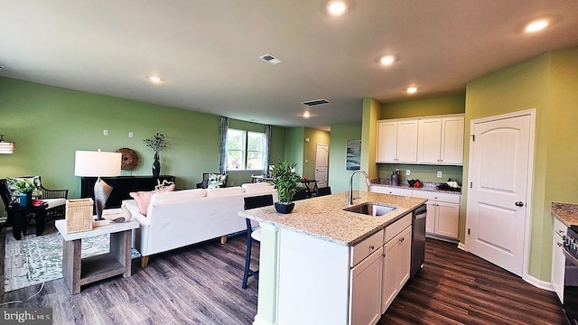 kitchen featuring an island with sink, light stone counters, white cabinets, dark wood-type flooring, and sink