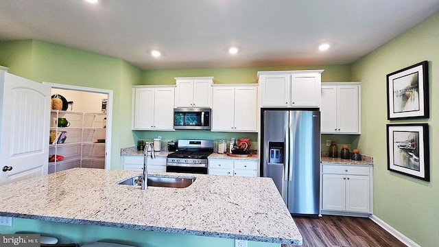 kitchen featuring white cabinets, appliances with stainless steel finishes, sink, and a kitchen island with sink