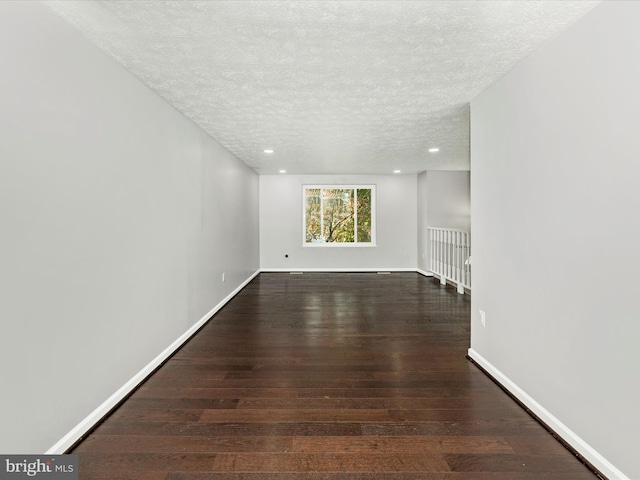 unfurnished room with dark wood-type flooring and a textured ceiling