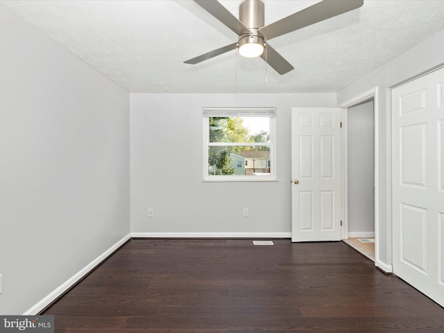 unfurnished bedroom with dark wood-type flooring, ceiling fan, and a textured ceiling