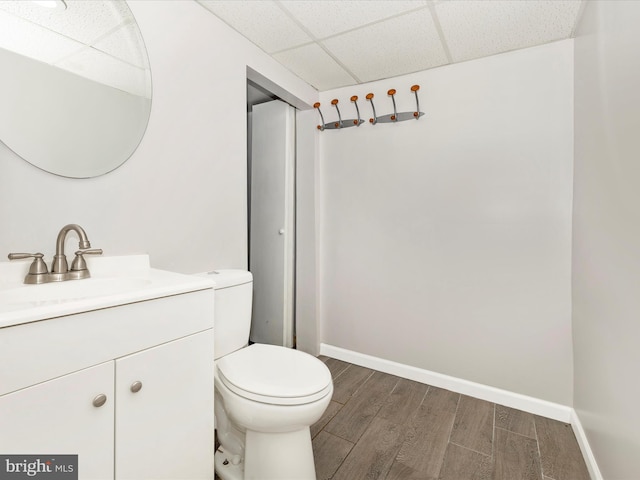 bathroom with vanity, hardwood / wood-style flooring, a paneled ceiling, and toilet