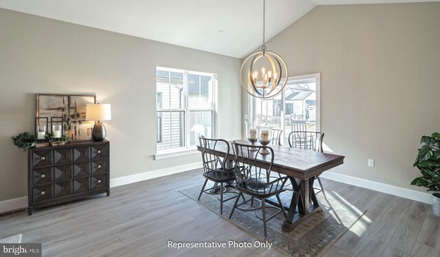 dining area with wood-type flooring, lofted ceiling, and a notable chandelier