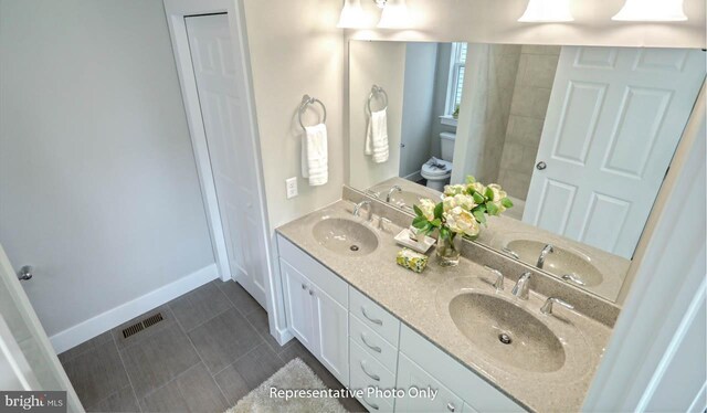 bathroom featuring tile patterned flooring, vanity, and toilet