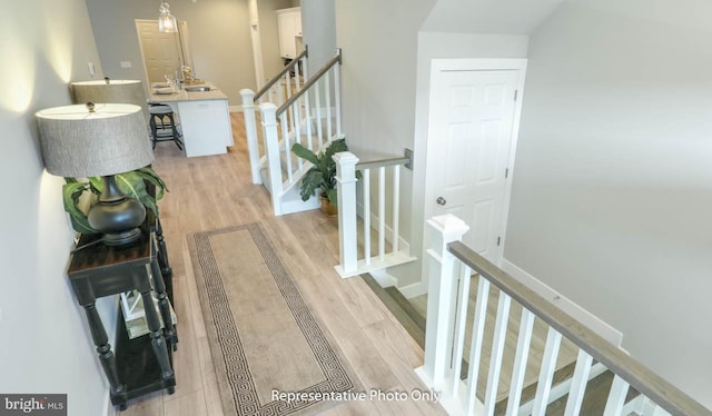 staircase with wood-type flooring and sink