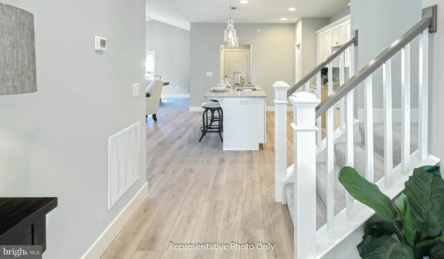 hall with light hardwood / wood-style floors and sink