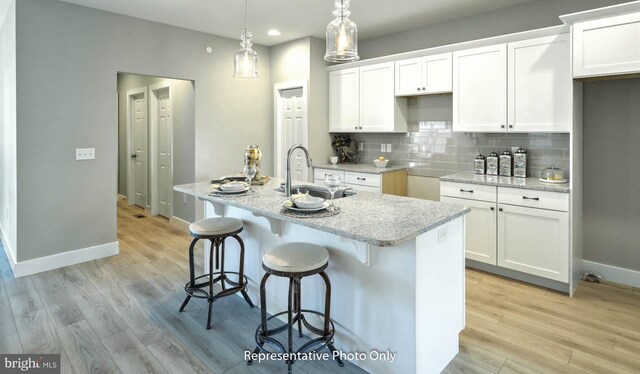 kitchen with sink, white cabinetry, and an island with sink