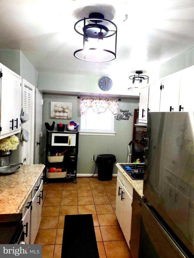 kitchen featuring light tile patterned flooring, white cabinets, and stainless steel fridge