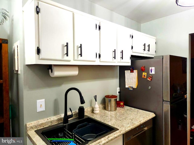 kitchen featuring white cabinetry, stainless steel fridge, black dishwasher, light stone countertops, and sink