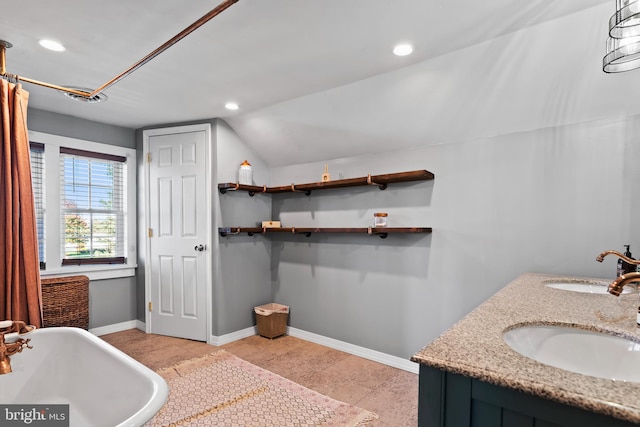 bathroom with a tub to relax in, sink, and vaulted ceiling