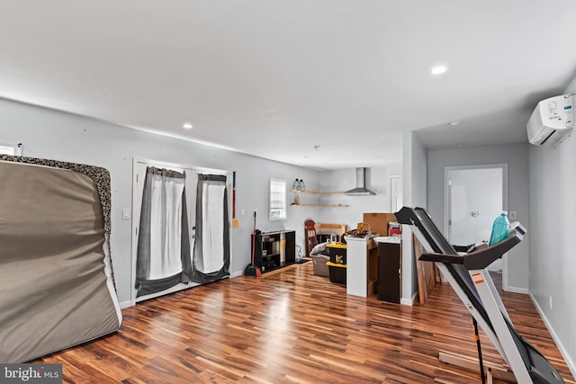 workout area with a wall mounted AC and hardwood / wood-style floors