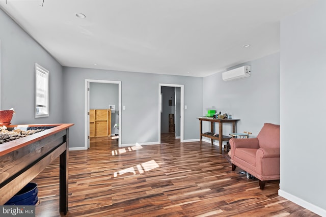 living area featuring dark wood-type flooring and a wall mounted air conditioner