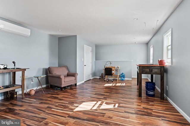 sitting room with a wall mounted AC and dark wood-type flooring