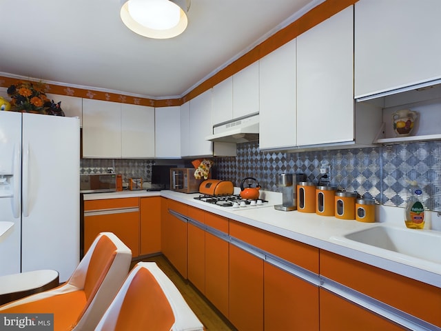 kitchen with white appliances, hardwood / wood-style floors, backsplash, white cabinets, and ornamental molding