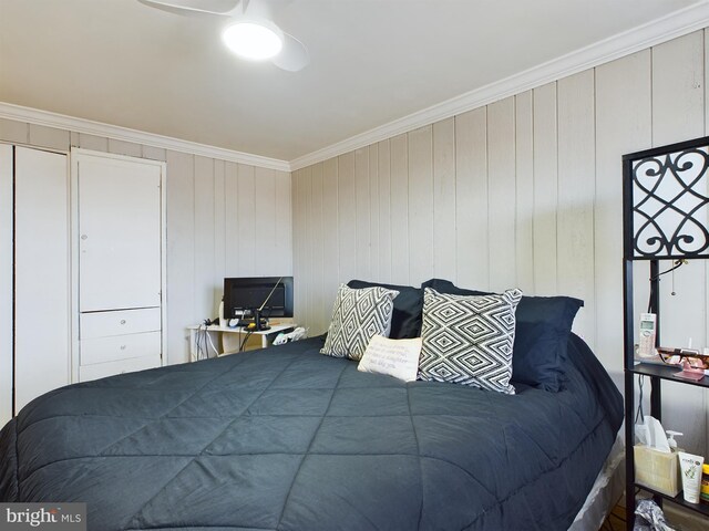 bedroom with ornamental molding, wooden walls, and ceiling fan