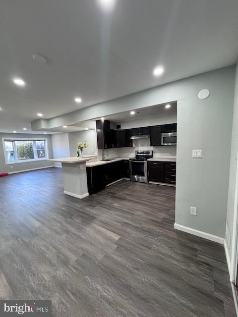 kitchen with sink, dark wood-type flooring, appliances with stainless steel finishes, and kitchen peninsula