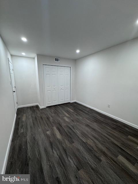 unfurnished bedroom featuring a closet and dark wood-type flooring