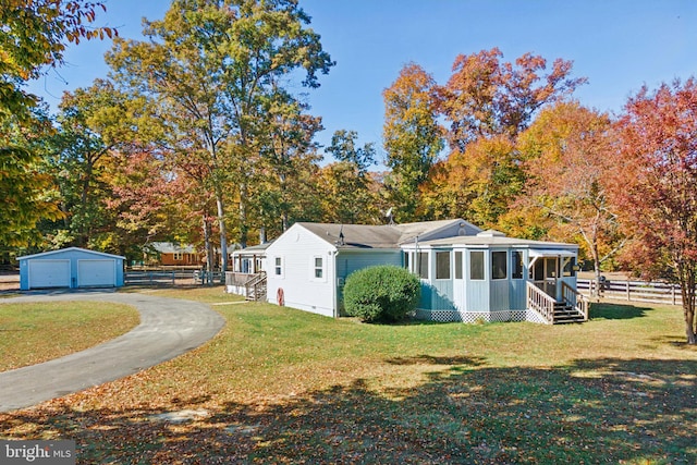 view of side of property featuring an outbuilding, a sunroom, a garage, and a lawn