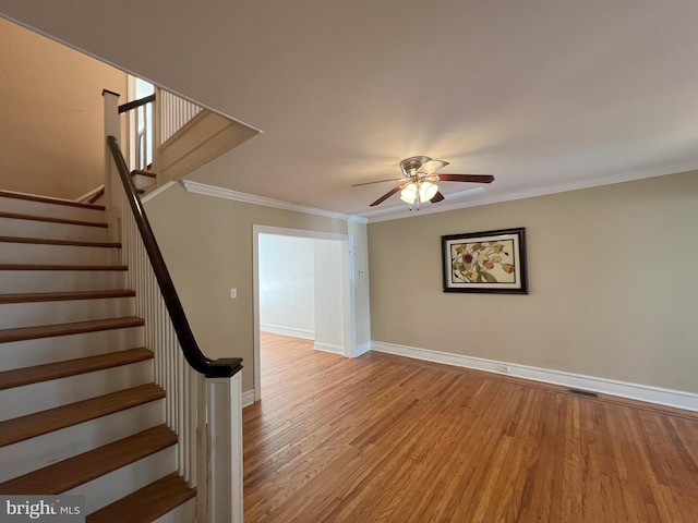 stairway featuring hardwood / wood-style floors, ceiling fan, and crown molding