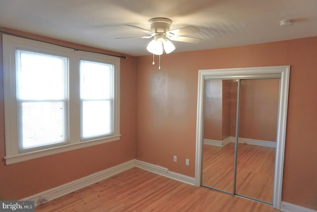 unfurnished bedroom with hardwood / wood-style flooring, ceiling fan, and a closet