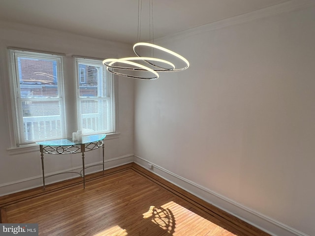 unfurnished dining area with hardwood / wood-style flooring, ornamental molding, a healthy amount of sunlight, and a chandelier