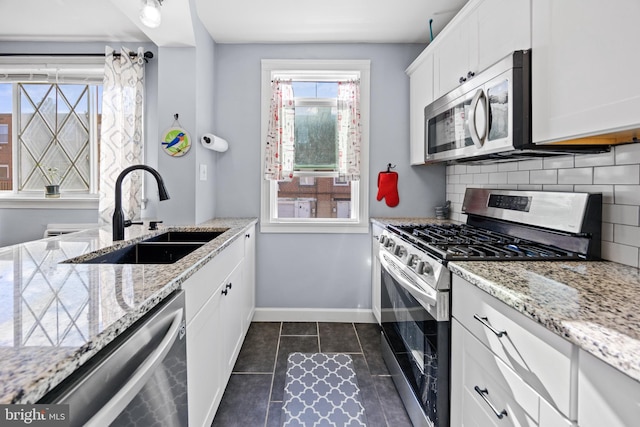 kitchen with white cabinets, tasteful backsplash, light stone countertops, sink, and stainless steel appliances