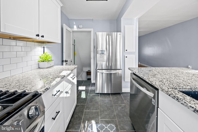 kitchen featuring light stone counters, stainless steel appliances, backsplash, and white cabinets