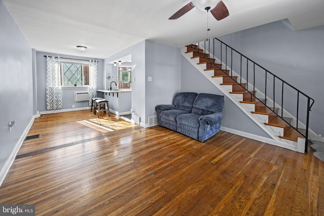 unfurnished living room with an AC wall unit, sink, hardwood / wood-style flooring, and ceiling fan