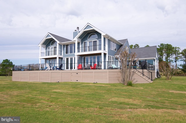 rear view of house featuring a balcony and a lawn