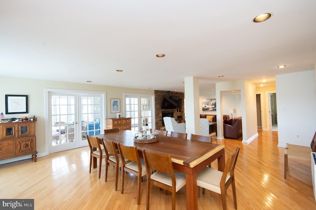 dining area featuring french doors, light hardwood / wood-style floors, and a large fireplace